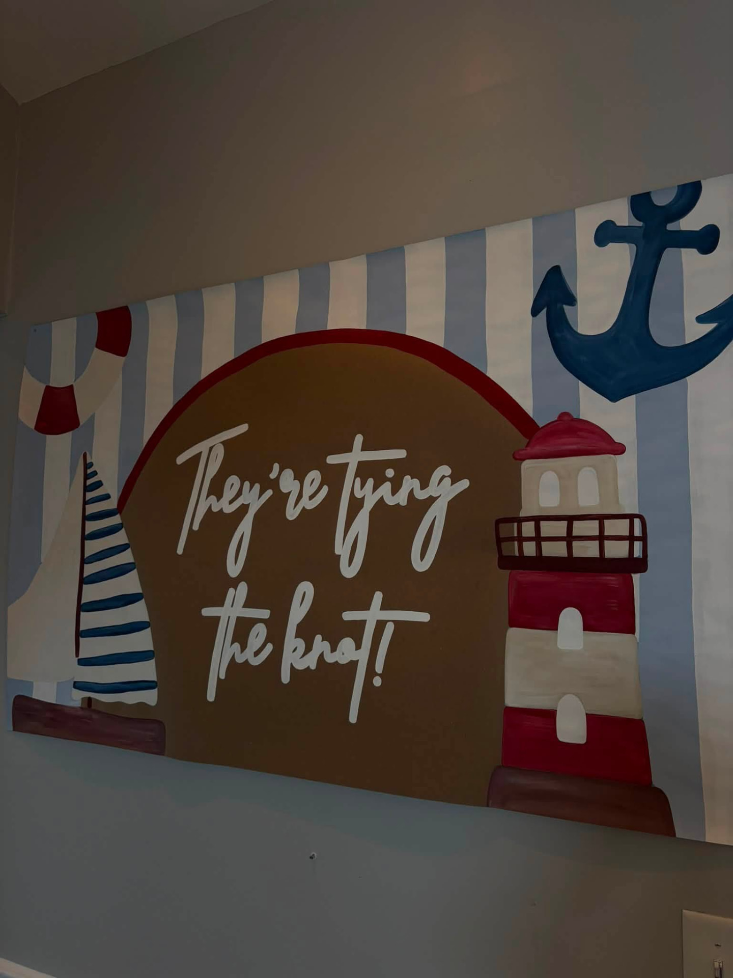 Hand-painted nautical wedding banner with a lighthouse, sailboat, anchor, and the words They're tying the knot
